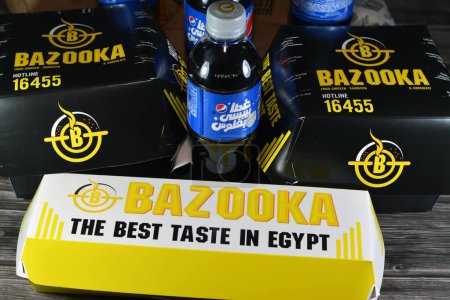 Téléchargez les photos : Le Caire, Egypte, 30 avril 2023 : Bazooka fast food package de hamburgers de poulet, fajita wraps, frites et boissons gazeuses, Bazooka est un restaurant situé en Egypte, servant une sélection de Burgers - en image libre de droit