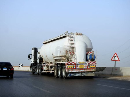 Téléchargez les photos : Le Caire, Égypte, 20 mai 2023 : Un grand camion avec un réservoir de conteneurs contenant des produits pétroliers, un camion sur l'autoroute avec un conteneur sur lui livrant les produits à usage industriel, foyer sélectif - en image libre de droit