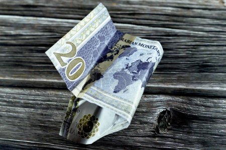 Téléchargez les photos : Crumpled Saudi Arabia money of 20 SAR twenty riyals with G20 summit logo, photo du roi Salman, carte du monde, billets de trésorerie ridés, inflation monétaire saoudienne et concept de crise économique mondiale - en image libre de droit
