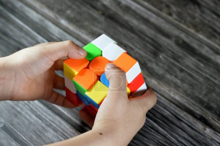 Photo for Cairo, Egypt, May 26 2023: Solving the Rubik's Cube by a child, combination puzzle, speed magic puzzle cube, each of the six faces was covered by nine stickers, each of one of six solid colors - Royalty Free Image