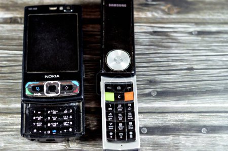 Foto de El Cairo, Egipto, 26 de mayo de 2023: Antiguo teléfono móvil Samsung giratorio móvil con teclado y botones que gira 180 grados, Samsung y el viejo teléfono móvil Nokia N95 deslizante, vintage retro - Imagen libre de derechos