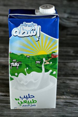 Photo for Cairo, Egypt, May 30 2023: Eshta full cream fresh cow's milk carton bottle of 1 one Liter litre, selective focus of Qeshta natural milk isolated on wooden background - Royalty Free Image