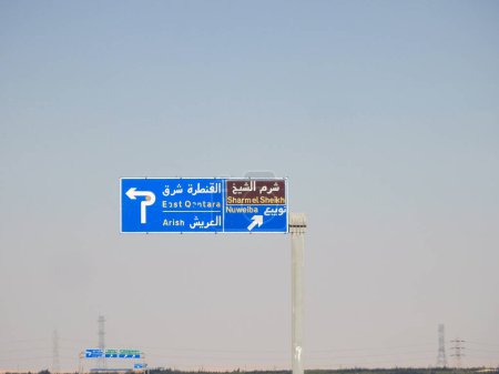 Téléchargez les photos : Un panneau indicatif de circulation latérale directionnelle dans le sud du Sinaï donne des directions de Sharm El Sheikh, Qantara Est, villes d'Arish et Nuweiba sur l'autoroute écrite en arabe et en anglais - en image libre de droit