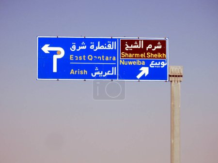 Téléchargez les photos : Un panneau indicatif de circulation latérale directionnelle dans le sud du Sinaï donne des directions de Sharm El Sheikh, Qantara Est, villes d'Arish et Nuweiba sur l'autoroute écrite en arabe et en anglais - en image libre de droit