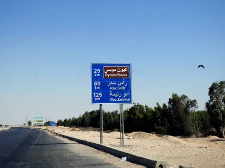 Téléchargez les photos : Sinaï Sud, Egypte, 30 juin 2023 : Un panneau de signalisation routière en arabe et en anglais montre la distance à Oyoun Mousa 25 KM, Ras Sudr ville 60 KM et Abu Zenima 125 KM sur Sharm El Sheikh Road dans le Sinaï - en image libre de droit