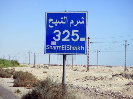 Photo for A road sign board in Sharm El Sheikh highway gives the remaining distance to Sharm 325 KM kilometers written in English and word Sharm Al Shiekh written in Arabic and English at the side of the street - Royalty Free Image