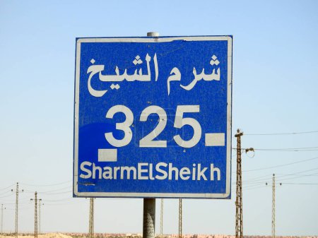Téléchargez les photos : Un panneau de signalisation à Sharm El Sheikh autoroute donne la distance restante à Sharm 325 KM kilomètres écrits en anglais et mot Sharm Al Shiekh écrit en arabe et en anglais sur le côté de la rue - en image libre de droit