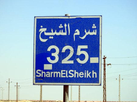 Téléchargez les photos : Un panneau de signalisation à Sharm El Sheikh autoroute donne la distance restante à Sharm 325 KM kilomètres écrits en anglais et mot Sharm Al Shiekh écrit en arabe et en anglais sur le côté de la rue - en image libre de droit