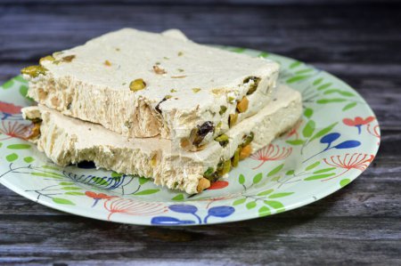 Photo for Traditional tahini halva with pistachios or Halawa Tahiniya, the primary ingredients in this confection are sesame butter or paste (tahini) sugar, glucose or honey, it is basic tahini and sugar base - Royalty Free Image