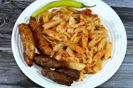 Photo for A plate of classic pasta penne macaroni with tomato sauce, Egyptian classic homemade sausage of deep fried stuffed mumbar which is basically intestines that are filled with spicy rice, Rice kofta - Royalty Free Image