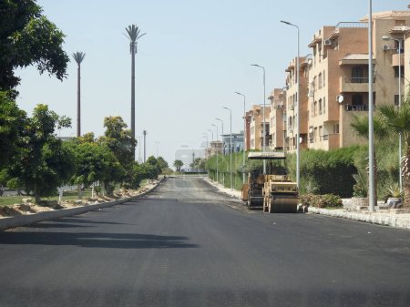 Foto de El Cairo, Egipto, 21 de julio de 2023: el proceso de pavimentar una carretera y hacer emulsión de asfalto en la construcción de nuevas carreteras en Egipto proyectos inmobiliarios después de la nivelación del suelo por camión nivelador y nivelador láser - Imagen libre de derechos