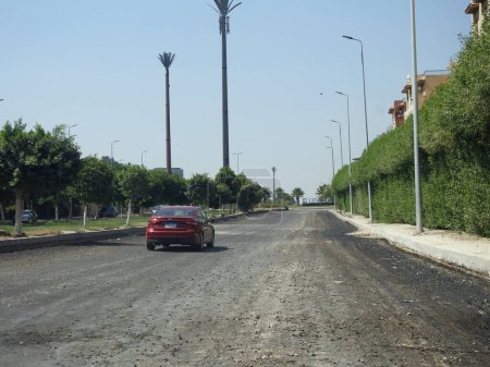 Foto de El Cairo, Egipto, 21 de julio de 2023: el proceso de pavimentar una carretera y hacer emulsión de asfalto en la construcción de nuevas carreteras en Egipto proyectos inmobiliarios después de la nivelación del suelo por camión nivelador y nivelador láser - Imagen libre de derechos