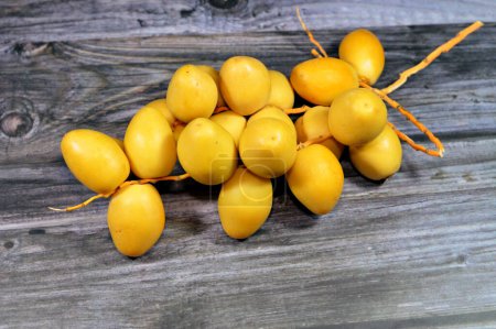 Photo for Yellow Barhi dates, botanically classified as Phoenix dactylifera, fruits of a date palm belonging to the Arecaceae family, native to Iraq, one of the sweetest-known date varieties with sugar content - Royalty Free Image