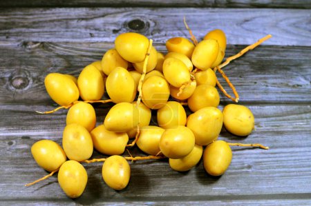 Photo for Yellow Barhi dates, botanically classified as Phoenix dactylifera, fruits of a date palm belonging to the Arecaceae family, native to Iraq, one of the sweetest-known date varieties with sugar content - Royalty Free Image