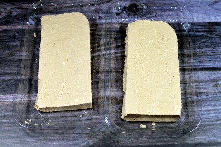 Téléchargez les photos : Tahini halva plaine traditionnelle ou Halawa Tahiniya, les principaux ingrédients de cette confiserie sont le beurre ou la pâte de sésame (tahini), et le sucre, le glucose ou le miel, il est base de tahini et de sucre - en image libre de droit