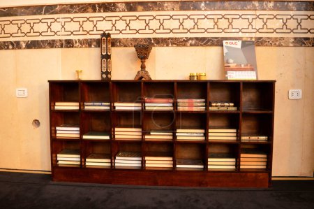 Foto de El Cairo, Egipto, 17 de septiembre de 2023: Libros de texto del Corán dentro de una estantería de madera en diferentes tamaños, una estantería de madera con una pila de libros de texto del Corán y mabjará o Bakhoor Incense Burner - Imagen libre de derechos
