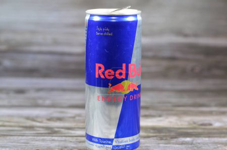 Foto de El Cairo, Egipto, 1 de octubre de 2023: Red Bull energy drink can, una marca de bebidas energéticas creada y propiedad de la empresa austriaca Red Bull GmbH, Su lema, (Red Bull Gives You Wings), aislado en madera - Imagen libre de derechos