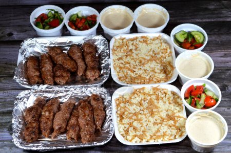 Photo for Arabic cuisine traditional food beef Kofta, kufta shish, minced meat wrapped in lamb fat charcoal grilled, with green and Tahini salad and hot steamed Egyptian white rice with vermicelli - Royalty Free Image
