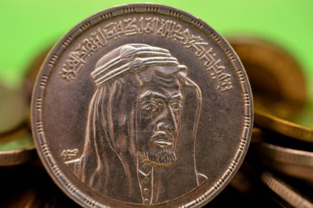 Photo for Obverse side of an Egyptian one pound coin, 1 LE coin year 1976, 1396 AH with Bust of King Faisal half right, Translation (Commemoration of His Majesty King Faisal bin Abdulaziz) on blurred coins - Royalty Free Image
