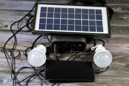 Foto de Una batería multipropósito cargada con un panel solar, un dispositivo que convierte la luz solar en electricidad mediante el uso de células fotovoltaicas (PV), con el teléfono celular de carga a través del puerto USB y la luz led conectada - Imagen libre de derechos