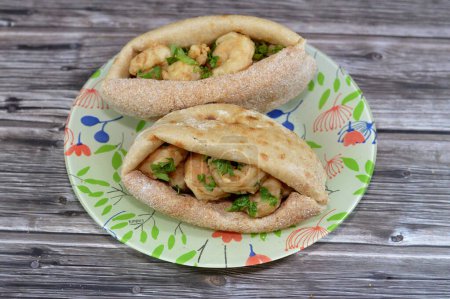 Photo for Fried shrimps covered with flour and fried in deep hot oil, a sandwich of fried shrimps in a traditional Egyptian flat bread with wheat bran and flour, regular Aish Baladi or Egypt bread - Royalty Free Image