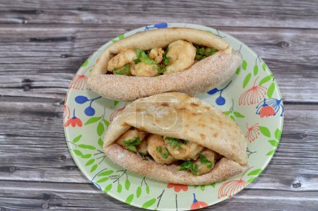 Photo for Fried shrimps covered with flour and fried in deep hot oil, a sandwich of fried shrimps in a traditional Egyptian flat bread with wheat bran and flour, regular Aish Baladi or Egypt bread - Royalty Free Image