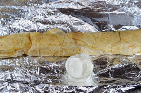 Téléchargez les photos : Long poulet syrien shawerma ou shawarma tortilla envelopper 50 CM avec oignon, tomate, laitue et sauce à l'ail dans le pain syrien, concept de cuisine arabe, enveloppé shawerma avec tomeya, accent sélectif - en image libre de droit