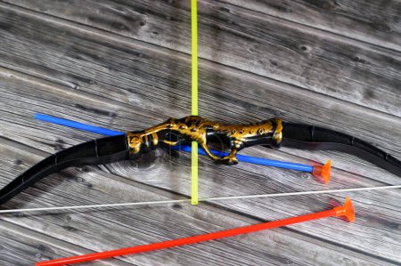 Photo for A plastic toy of a bow and arrows, Archery, The bow and arrow is a ranged weapon system consisting of an elastic launching device (bow) and long-shafted projectiles (arrows), kids' tool - Royalty Free Image