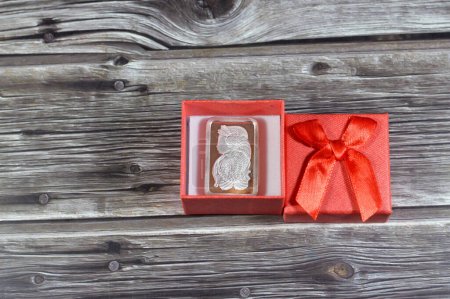 A red gift box with silver precious metal ounce bar of pure silver, The price of silver is driven by speculation, supply and demand and it's usually bought as an investment like other precious metals