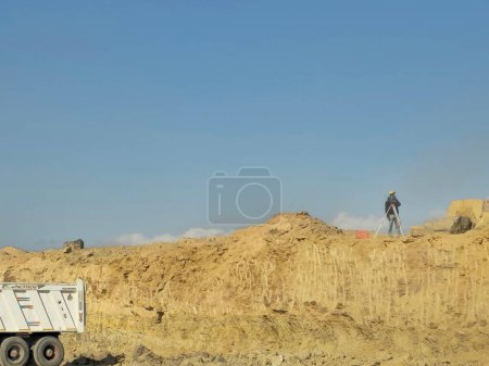 Photo for Cairo, Egypt, March 23 2024: An engineer and ground leveling with laser leveler in the process of paving a road before making asphalt emulsion in construction of new roads in Egypt, selective focus - Royalty Free Image