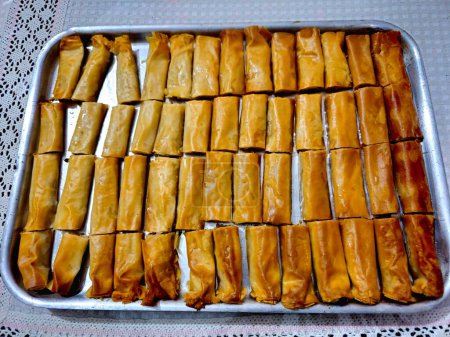 gerollte Baklava, ein süßes Dessert aus dem Nahen Osten, das mit Nüssen, Rosinen und geschredderten Kokosnüssen gefüllt und mit Honigzuckersirup, osttürkischer und ägyptischer Baklawa als Dessert im Ramadan-Monat getränkt ist