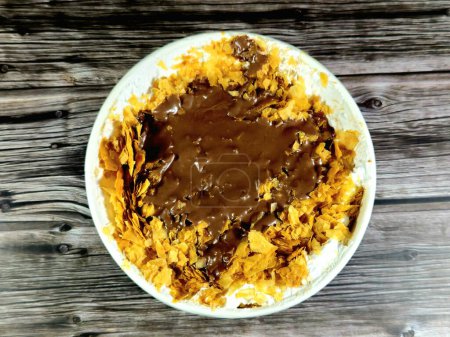chocolate paste sauce on top of Sweet Koshary recipe in Egypt made of multi layers of rice with milk sweet pudding, whipped cream, toasted Konafa and phyllo filo, with some other flavors and fillings