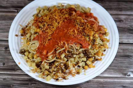 Ägyptische Küche von Koshary, ein beliebtes Streetfood aus Reis, Makkaroni, Spaghetti und Linsen gemischt mit einer gewürzten Tomatensauce, Knoblauchessig, gebratenen Zwiebeln und Hummus-Kichererbsen