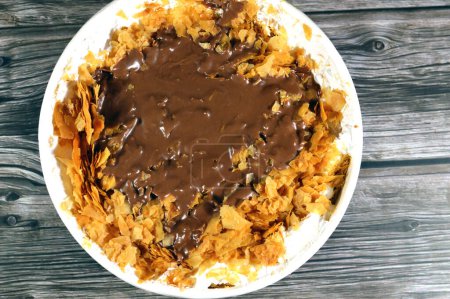 chocolate paste sauce on top of Sweet Koshary recipe in Egypt made of multi layers of rice with milk sweet pudding, whipped cream, toasted Konafa and phyllo filo, with some other flavors and fillings