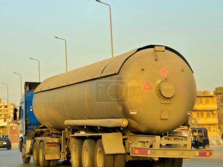 Téléchargez les photos : Gizeh, Egypte, le 17 mai 2024 : Un gros camion avec un réservoir contenant des produits pétroliers, un camion sur l'autoroute avec un conteneur sur lui livrant les produits à la station essence - en image libre de droit