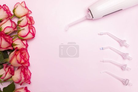 Happy International Dentist Day Rosenblüten, Mundspülmaschine, Zahnbürste auf rosa Hintergrund. Zahnpflege Grußkarte für den professionellen Urlaub.Copyspace, horizontale Ebene Platz für Text in der Mitte