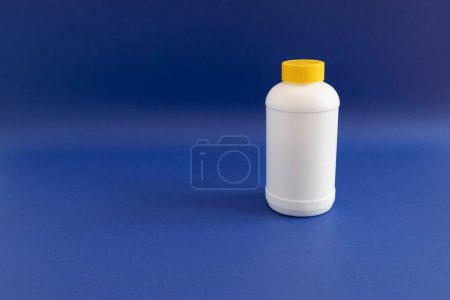 Photo for White Plastic Bottle, Yellow Cap With Pipe Granules Cleaner On Purple Blue Background. Removal Of Blockage In Sink, Shower With Special Chemicals. Cleaning Clog In Kitchen,Bathroom. Copyspace For Text - Royalty Free Image