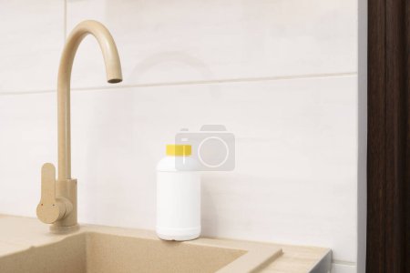 Photo for Plumber drain granules in White Plastic Bottle With Yellow Cap On Kitchen Sink In Cook Room. Clog Cleaner, Housework Help. Cleaning enzymes, Prevention of Blockages In Traps.Horizontal plane.CopySpace - Royalty Free Image