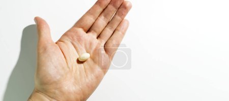 Pilule de progestérone de conception, capsules dans la main humaine sur fond blanc. La dose de médicaments traite le cycle menstruel irrégulier, les traitements de fertilité, l'hormonothérapie ménopausique, l'espace de copie horizontal.