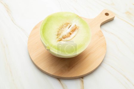 Photo for Cut Organic Honeydew Melon On Wooden Cutting Board on Granite Table, Cucumis Melo Inodorus Group. Ripe Nutritious Summer Juicy Fruit. Horizontal Plane. Harvesting, Top View. High quality photo - Royalty Free Image