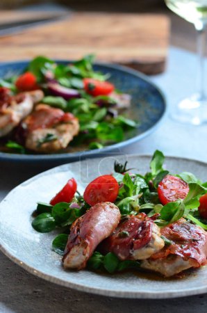 beautiful background of food served on a rustic plate, italian cuisine, grilled veal meat with parma ham and sage, mixed salad, close up view,