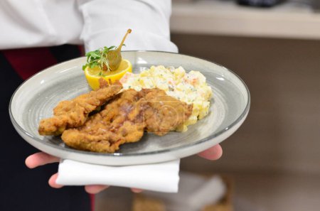 fried chicken with sauce and salad on plate, view of served veal steak from liver, Czech traditional food, restaurant background, close-up view