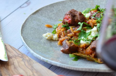 lamb stewed with tomatoes and orzo, background of greek traditional food youvetsi