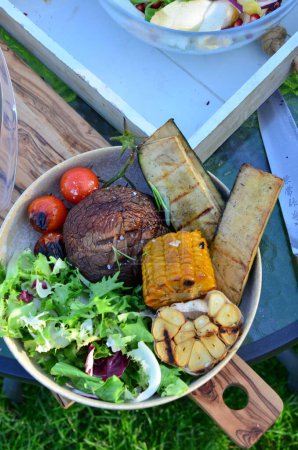 un gros plan de viande grillée sur une assiette et de légumes grillés avec de la viande grillée sur du bois