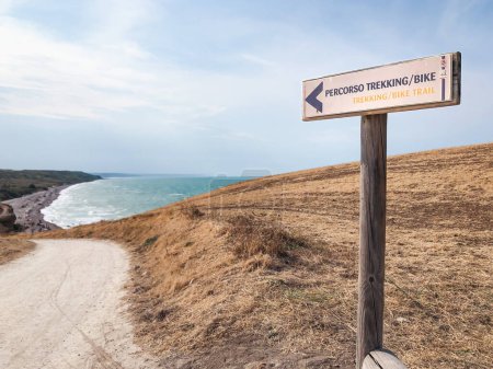 Photo for A sign indicates a trekking and biking route for tourists in a seaside resort on the Italian coast. Panoramic viewpoint of Punta Aderci with the sea, Vasto, Chieti, Italy - Royalty Free Image