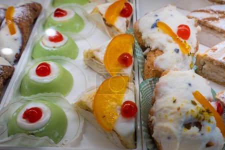 Téléchargez les photos : Bonbons traditionnels siciliens. Cassata sicilienne à l'orange et cerise confite. Pâtisseries traditionnelles siciliennes à la ricotta sucrée exposées dans une vitrine d'une pâtisserie - en image libre de droit