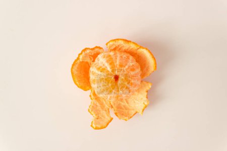 Top view of whole ripe peeled mandarin fruit with orange peels on a white background. Raw food diet and fruitarian concept. Space for text.