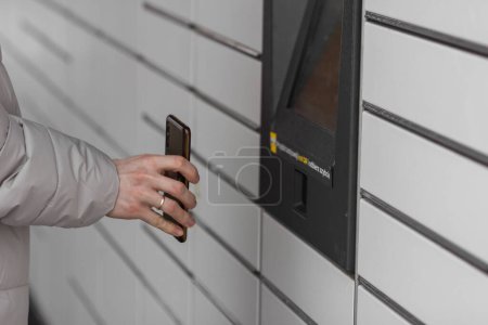 Photo for Pniewy, Poland - 22 January 2023. Man with smartphone entering QR code to open shopping locker in inPost delivery service. E-commerce shipping and delivery. People and gadgets concept. - Royalty Free Image