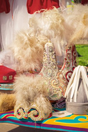 Téléchargez les photos : Coiffures kazakhes traditionnelles de filles faites à la main avec des plumes dans un magasin de marché de rue - en image libre de droit