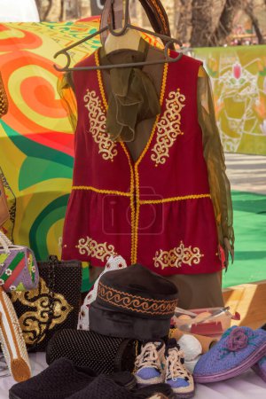 Téléchargez les photos : Robe traditionnelle kazakhe pour femme en velours avec des ornements nationaux dans un magasin de marché de rue. - en image libre de droit